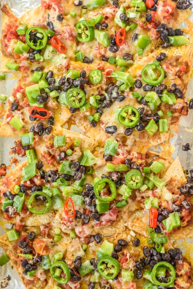 Sheet pan nachos with refried beans, black beans, salsa, cheese, jalapeños, and chopped peppers 