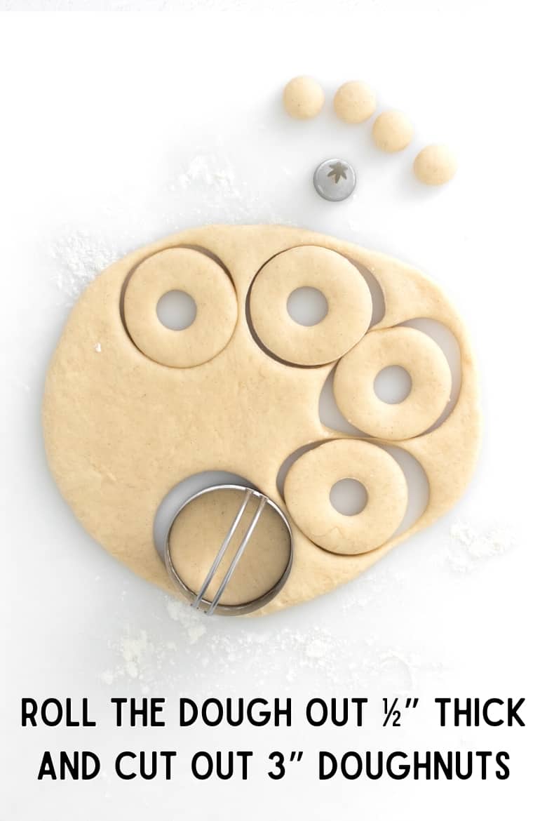 dough rolled out on floured surface and a cookie cutter cutting it into 3 inch circles with hole in the middle