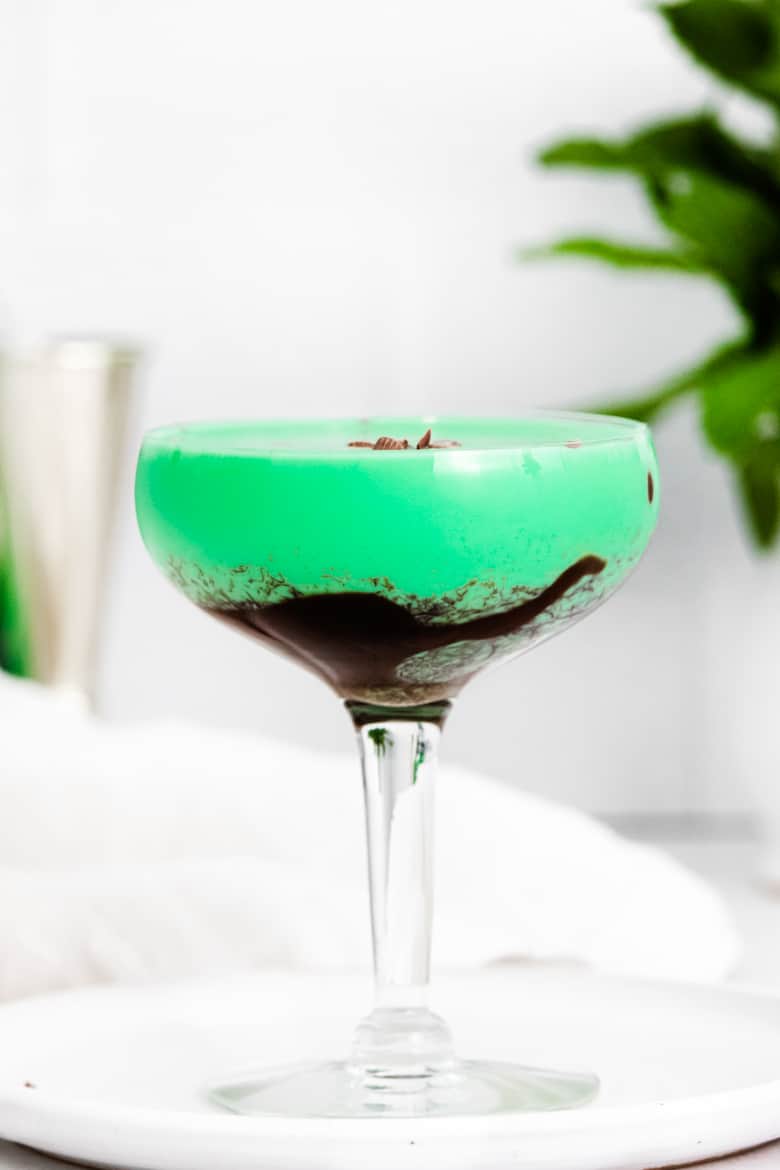 Bright green grasshopper drink in a cocktail glass drizzled with chocolate syrup