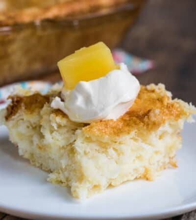 Square slice of 2 ingredient pineapple angel food cake topped with a dollop of whipped topping and a chunk of pineapple