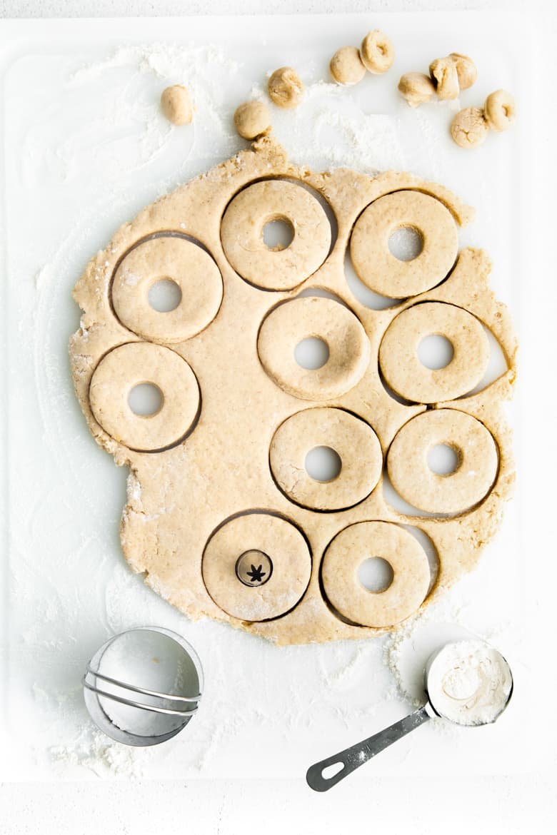 Doughnuts being cut out of dough using biscuit cutter and piping tip