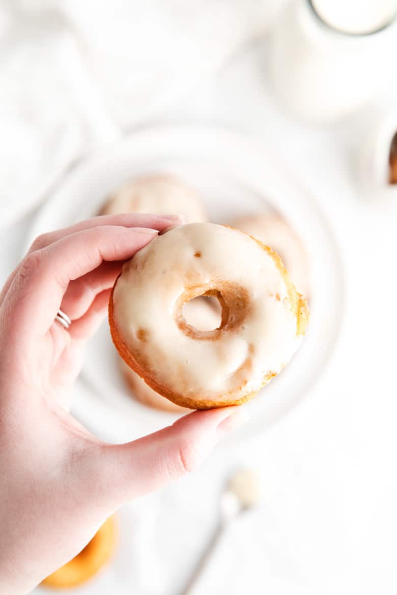woman's hand holding glazed old-fashioned doughnut 