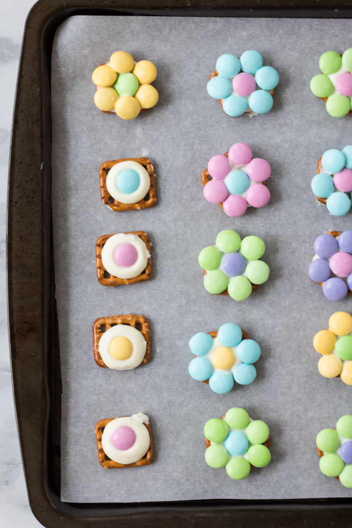 Flower pretzel bites completed and in progress. The in progress bites have an M&M in the center of each but do not yet have their "petals"