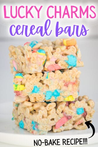 Three lucky charms marshmallow cereal bars cut into squares and stacked on top of one another on a white plate. Reads: Lucky Charms Cereal Bars; no-bake recipe