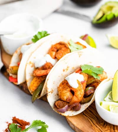 Sheet Pan Shrimp Fajitas served in flour tortillas topped with fresh cilantro and sour cream