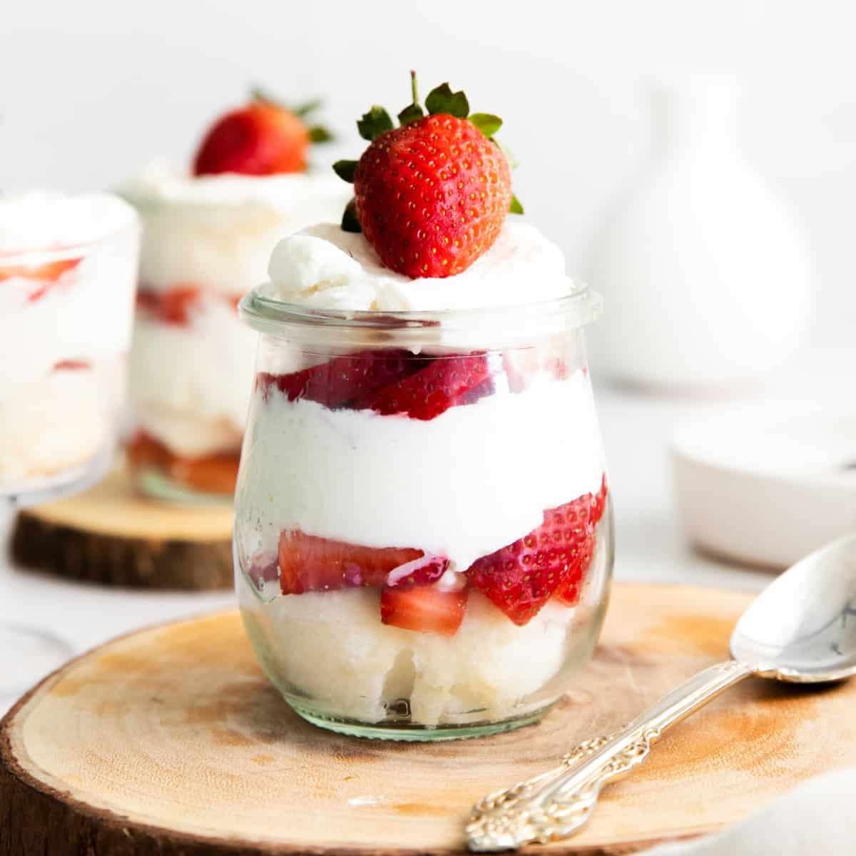 strawberry, angel food cake, and whipped cream trifle in small glass jar