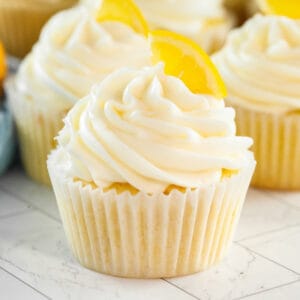 Lemon cupcakes topped with cream cheese frosting and garnished with a slice of lemon
