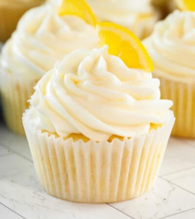 Lemon cupcakes topped with cream cheese frosting and garnished with a slice of lemon