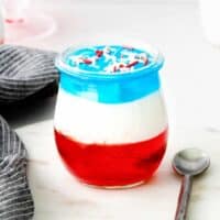 red, white, and blue layered jello cup topped with patriotic sprinkles