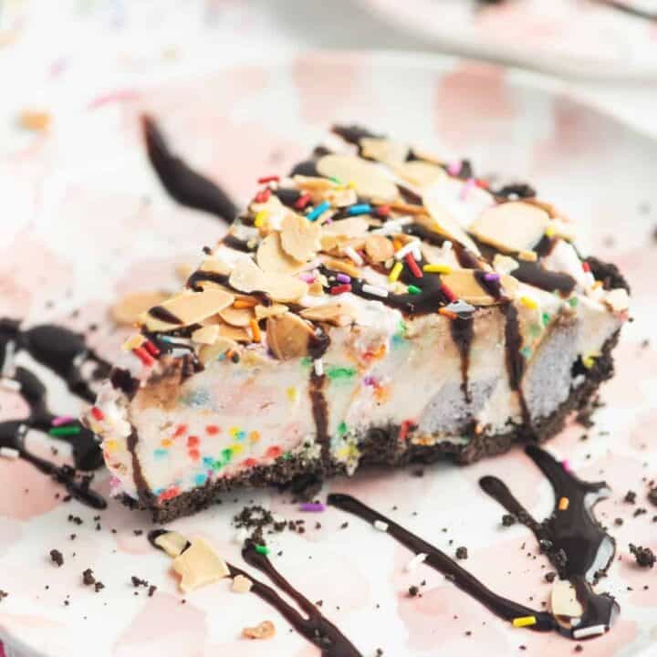 Slice of ice cream pie drizzled with chocolate sauce and topped with sprinkles and sliced almonds
