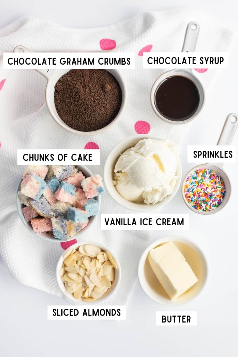 Ice cream pie ingredients: chocolate graham crumbs, chocolate sauce, chunks of cake, vanilla ice cream, rainbow sprinkles, sliced almonds, and butter