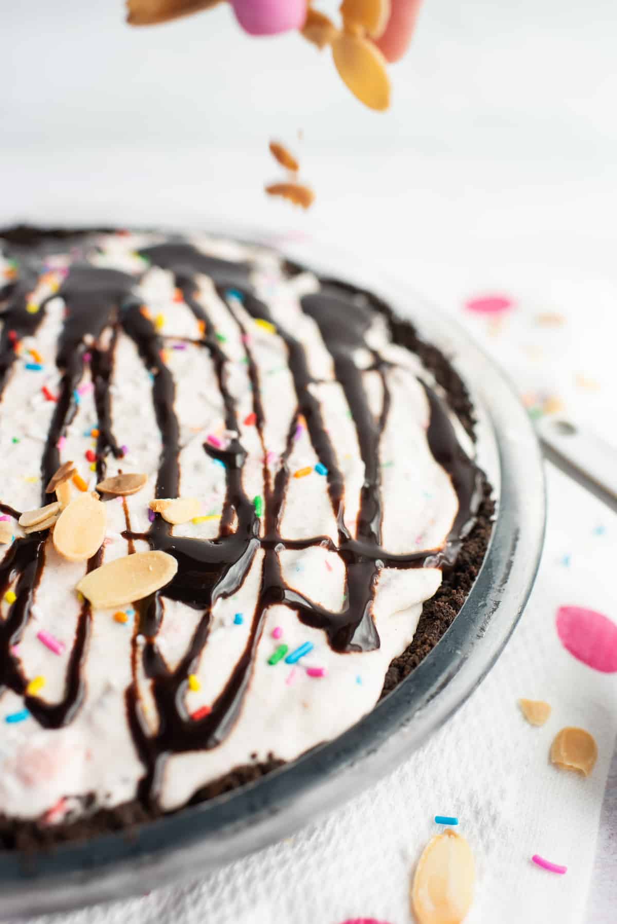 sliced almonds being sprinkled onto top of ice cream pie