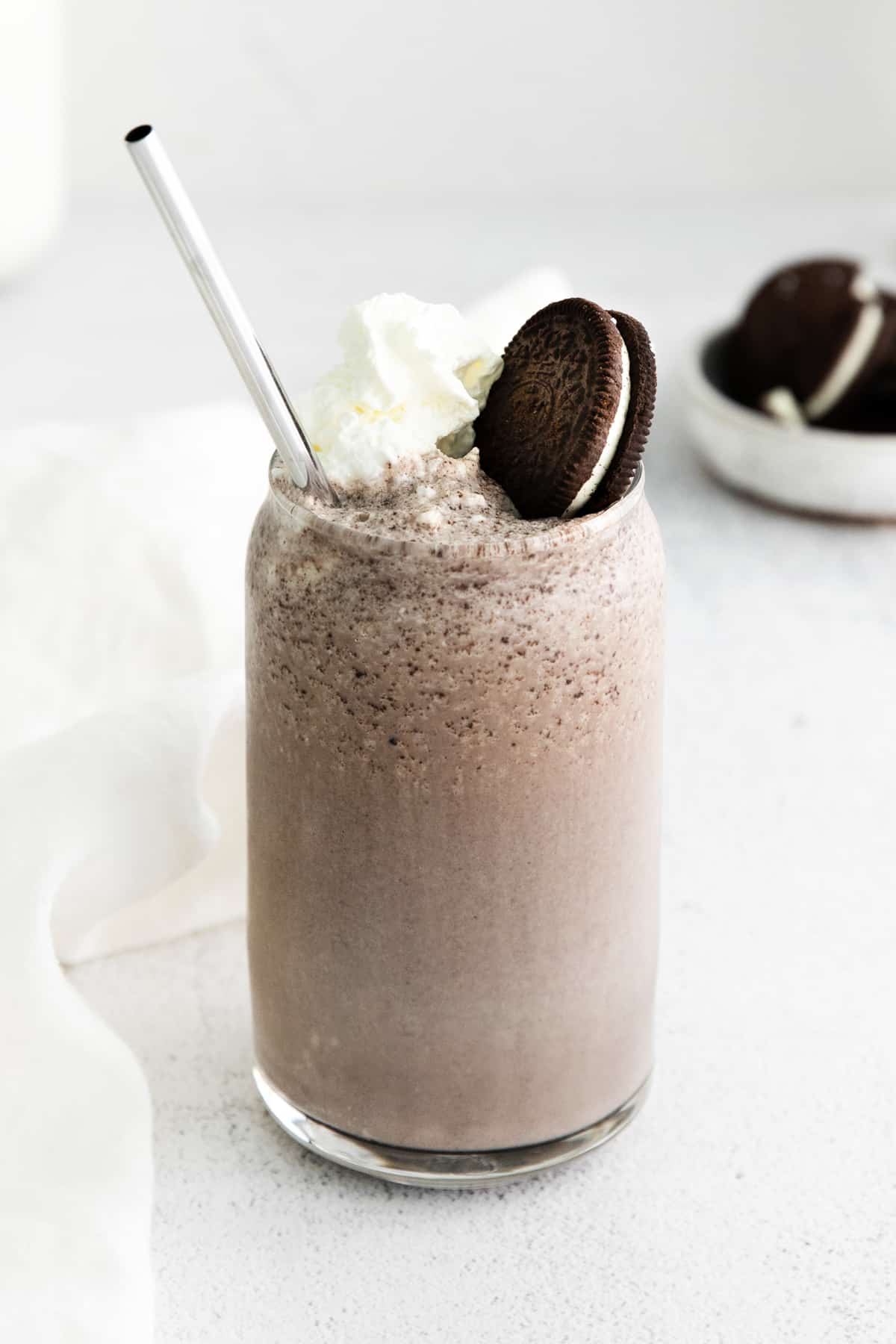 Boozy Oreo Milkshake in glass topped with whipped cream and an oreo cookie