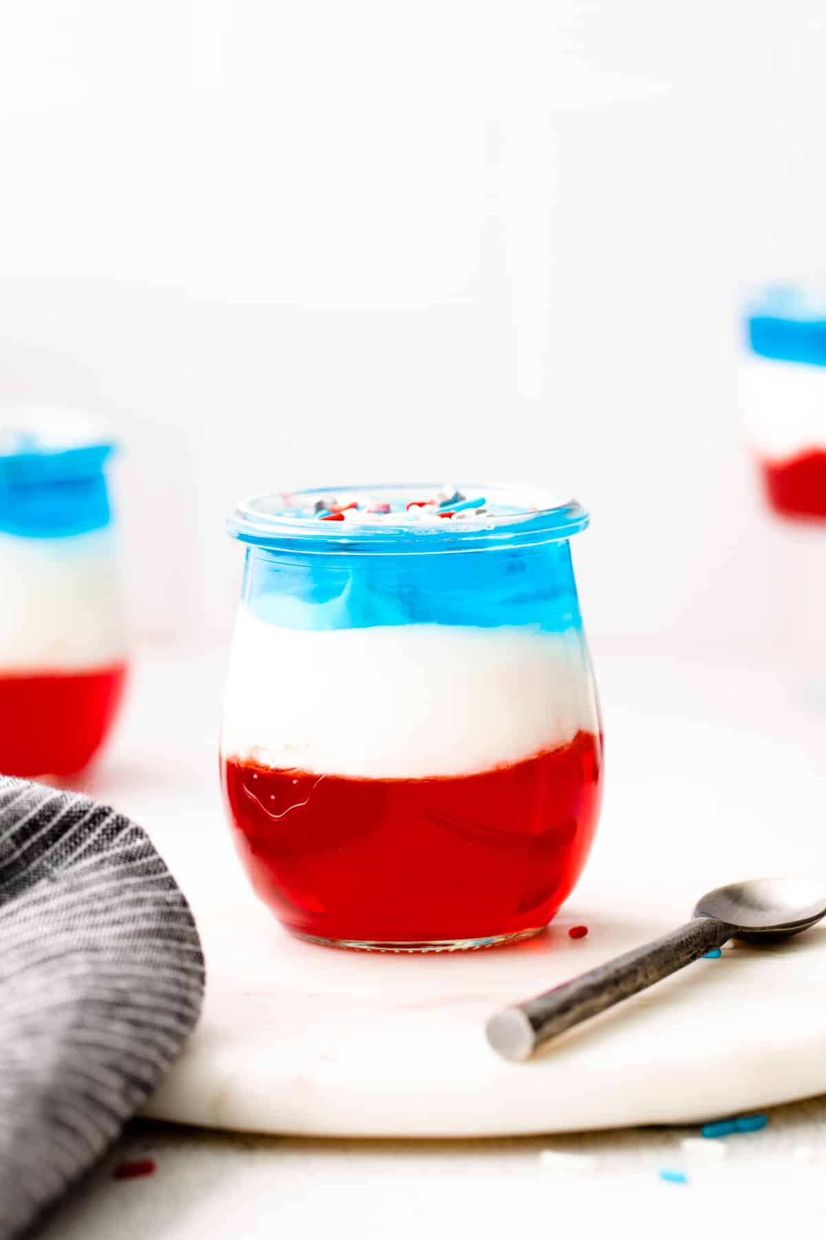 red, white, and blue layered jello cup topped with patriotic sprinkles