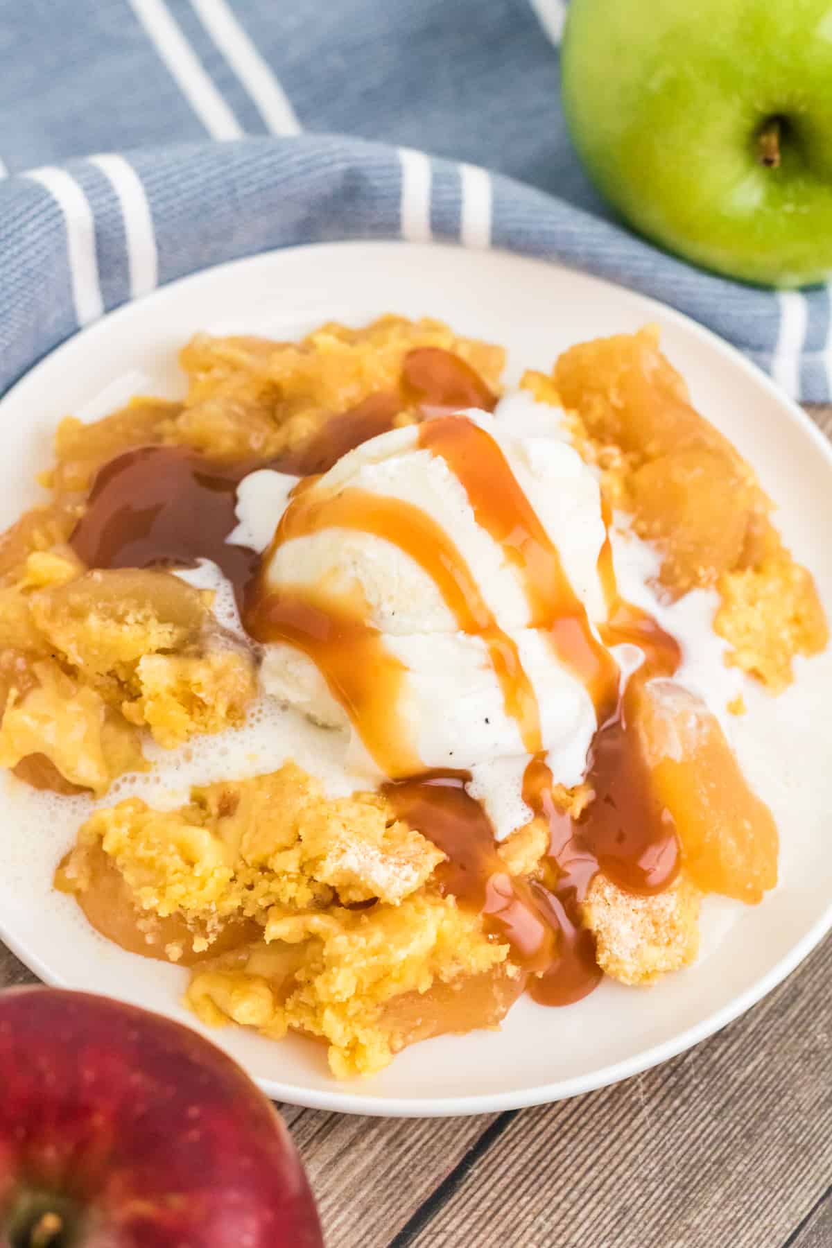 Apple dump cake with scoop of vanilla ice cream and drizzles with caramel sauce.