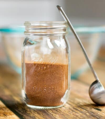 homemade apple pie spice in a small mason jar with small scoop next to it