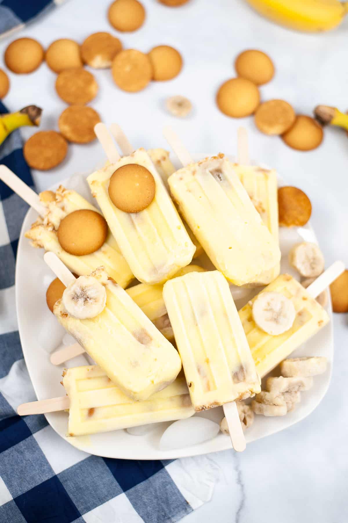 Banana popsicles piled on a platter with nilla wafers and frozen banana slices