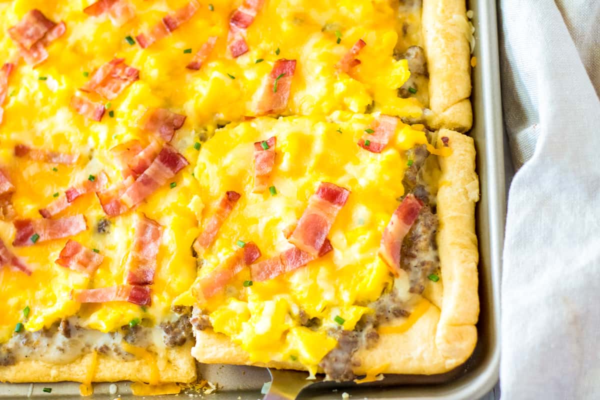 Square slice of breakfast pizza being removed with spatula.