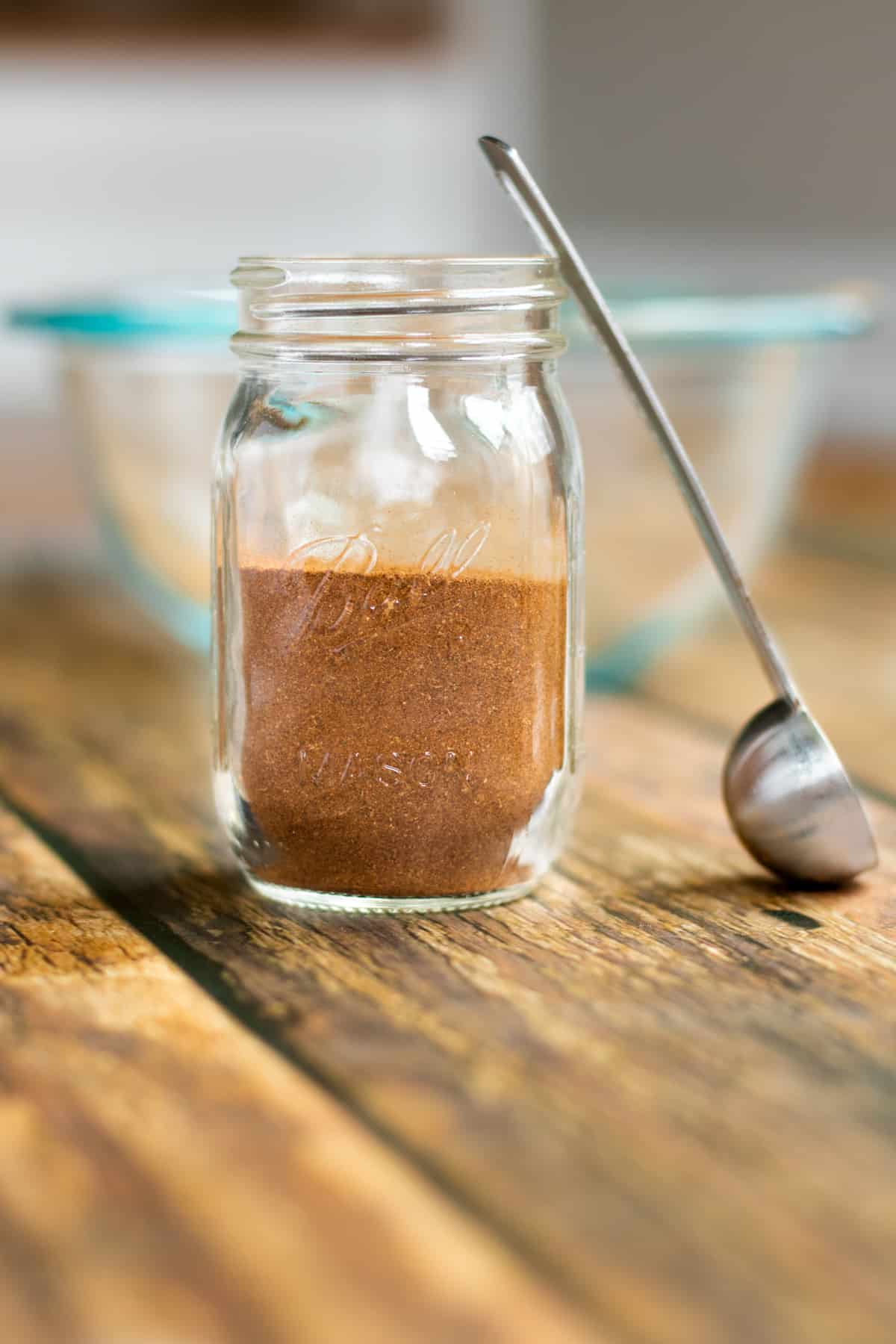 homemade apple pie spice in a small mason jar with small scoop next to it