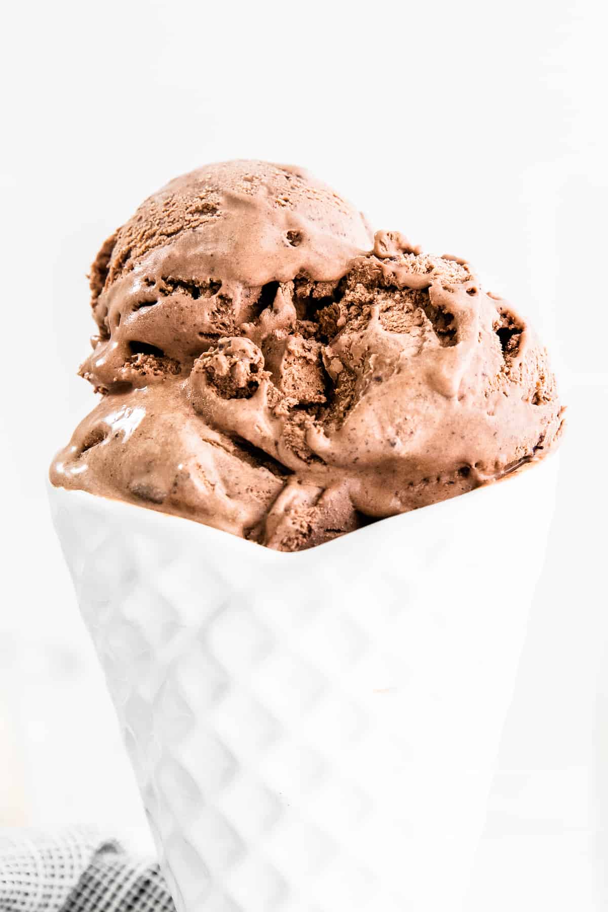 Rich and creamy no-churn chocolate ice cream in white bowl shaped like an ice cream cone