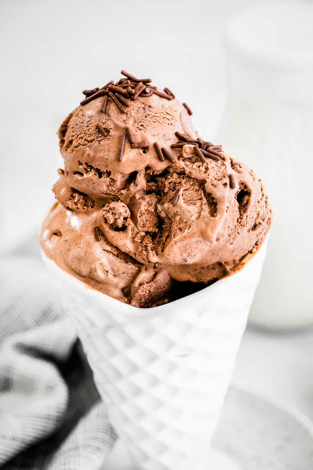 Homemade chocolate ice cream with chocolate sprinkles in white cone bowl