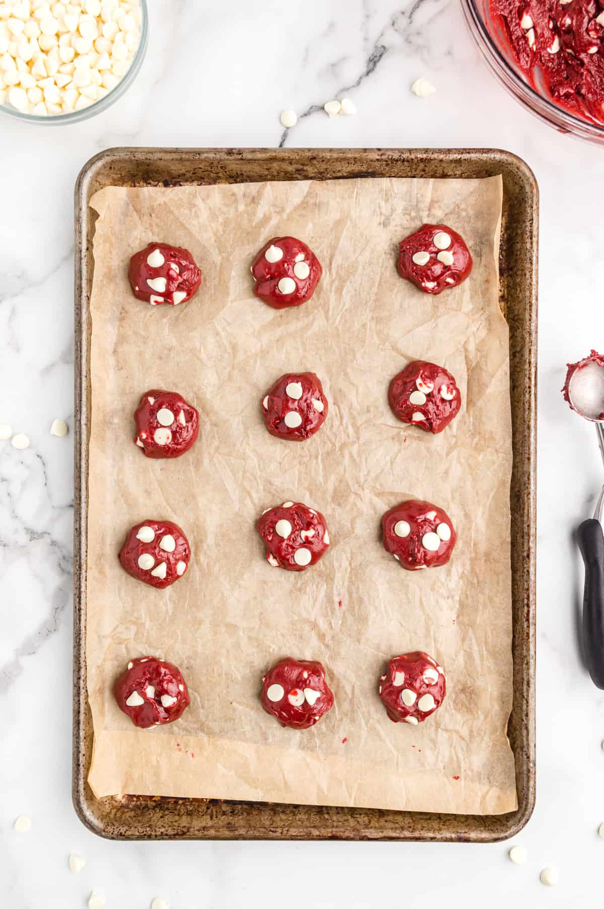12 balls of cookie dough on parchment lined baking sheet