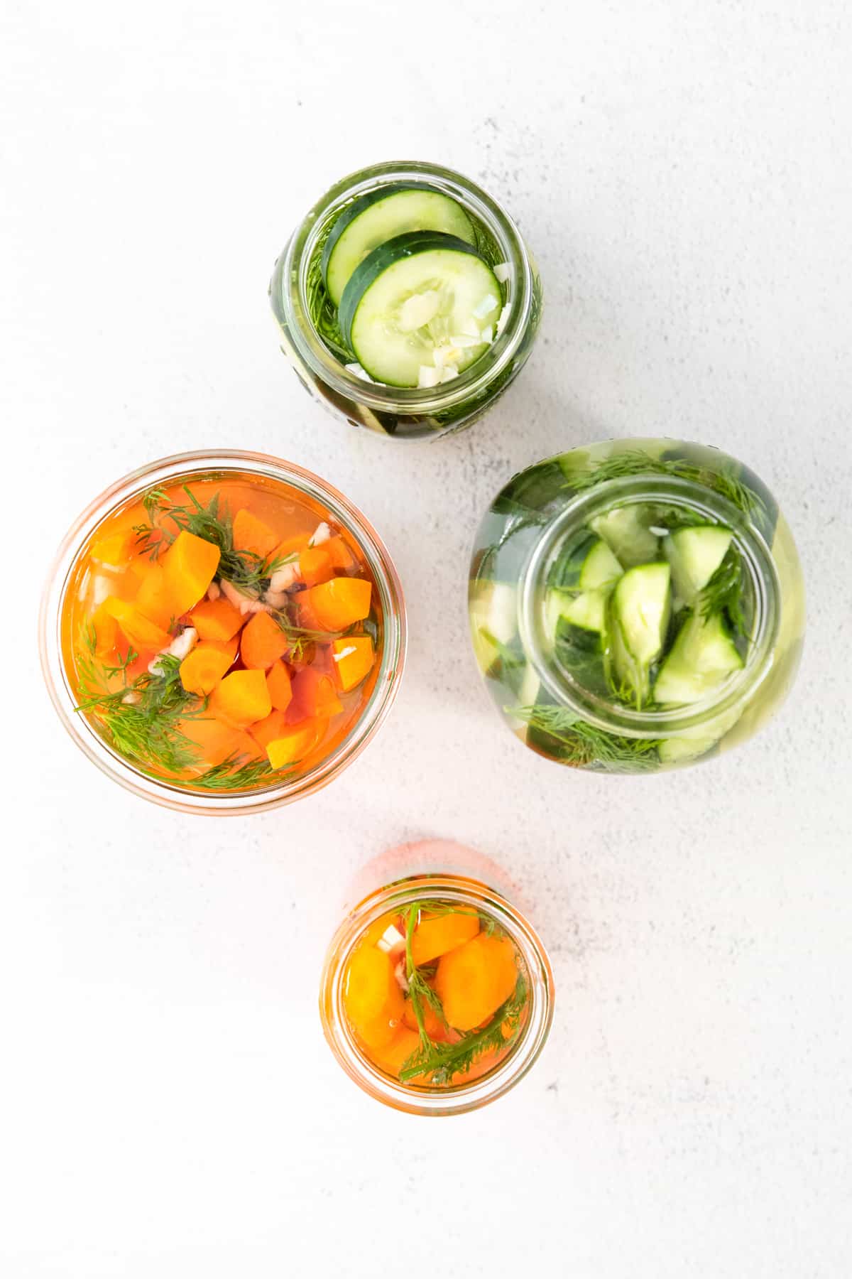 Mason jars covered filled with cucumbers and carrots covered in brine