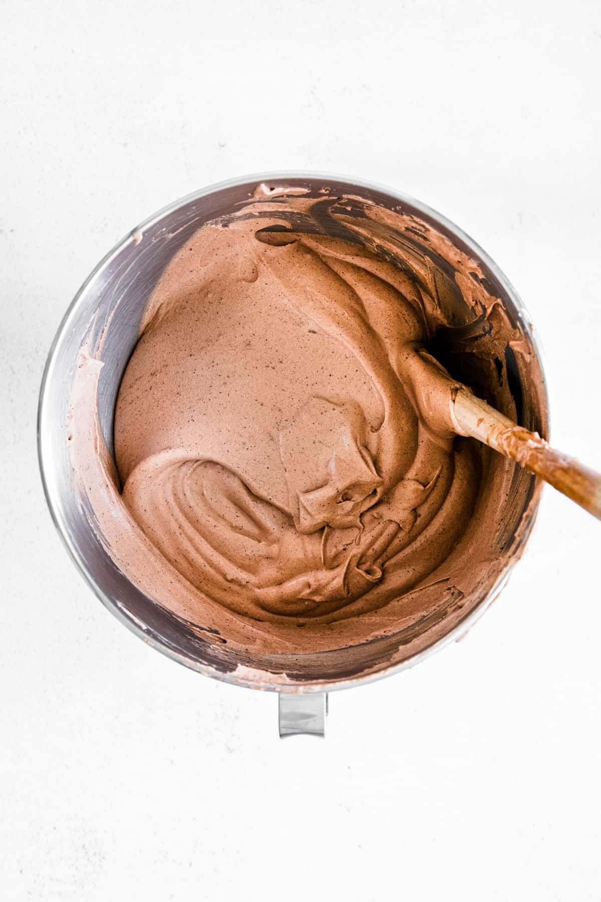 chocolate ice cream mixture in metal bowl with wooden spool