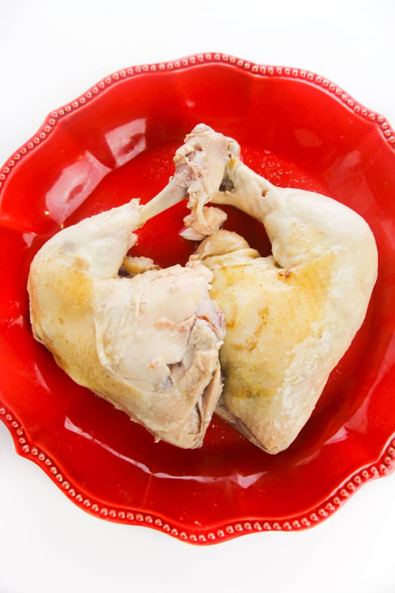 Pair of cooked chicken quarters on red plate