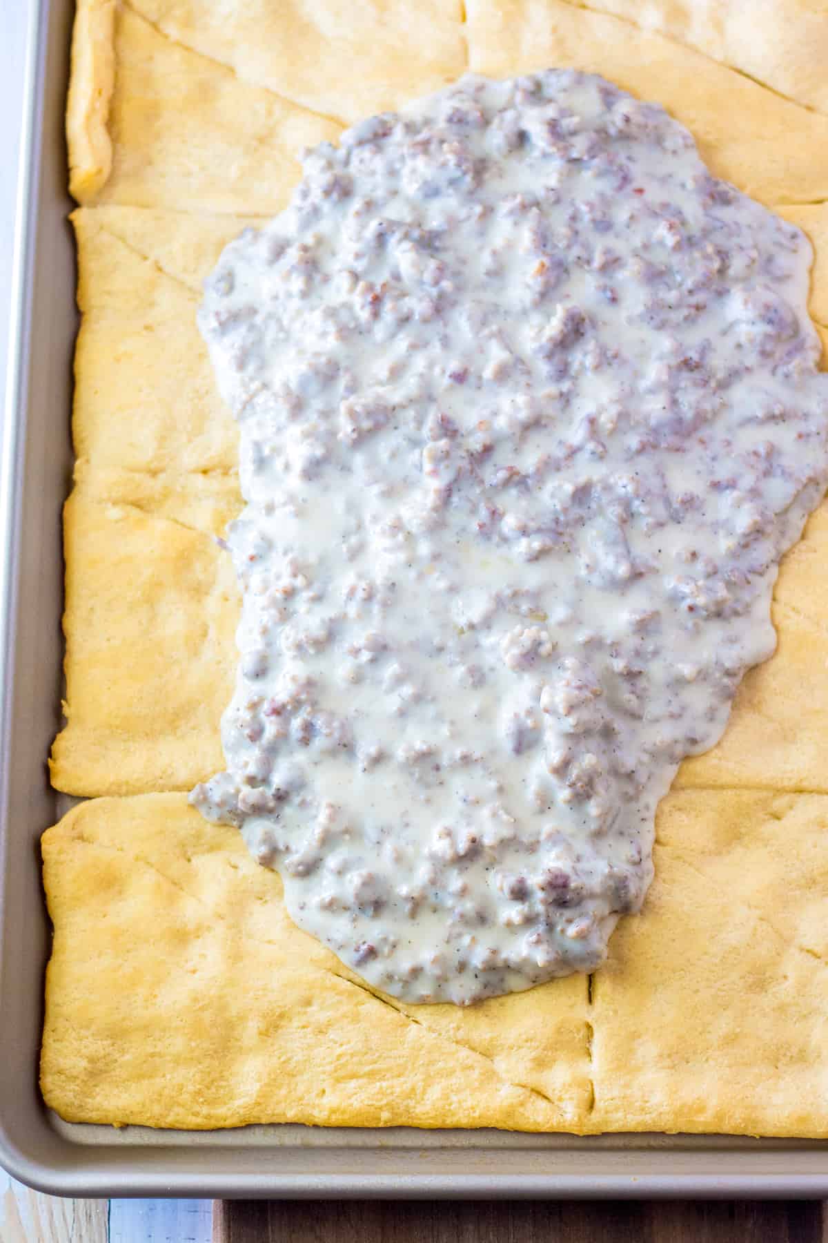 Sausage gravy spread on crescent roll crust.