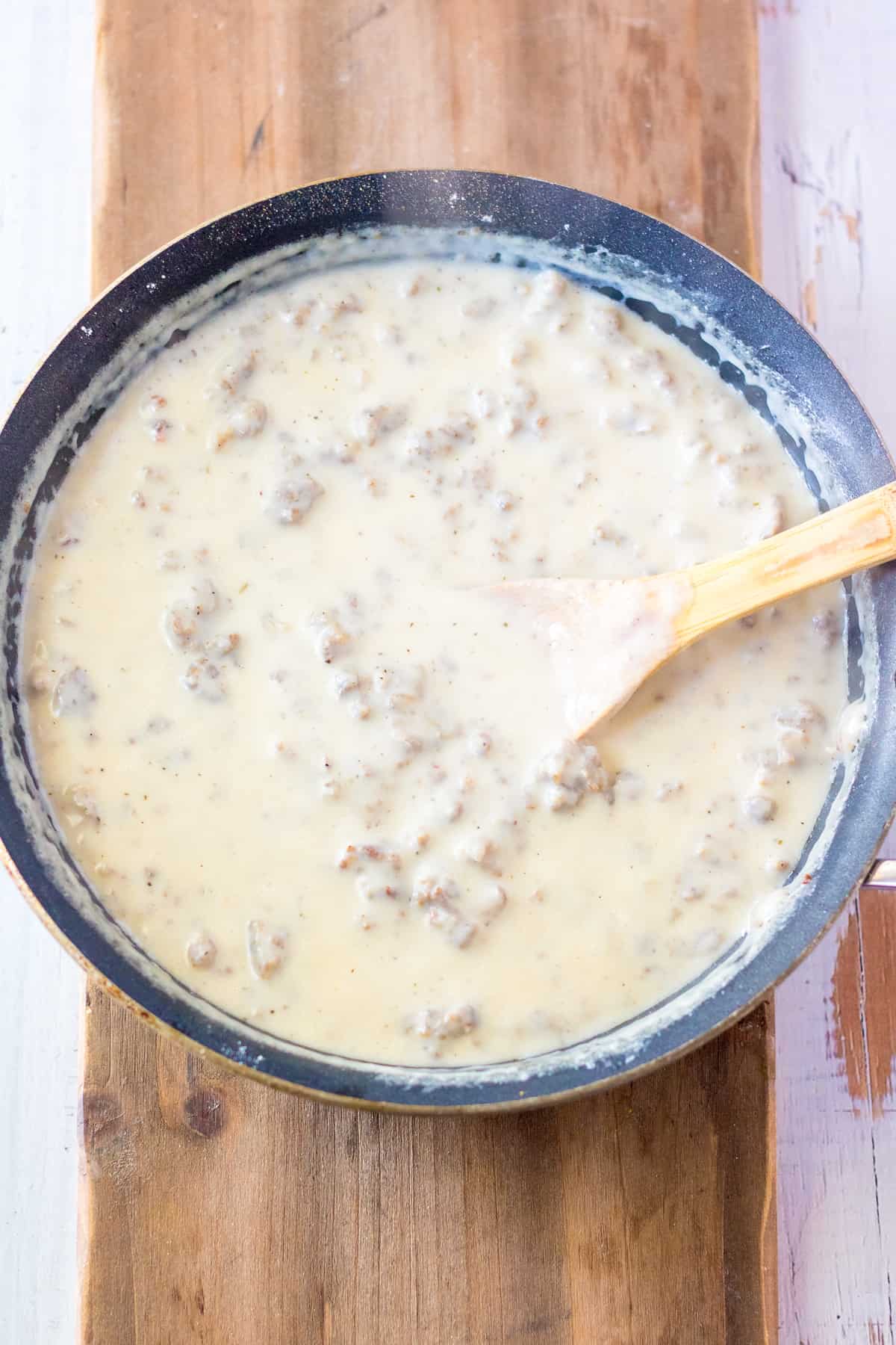 Sausage gravy in pan with wooden spoon