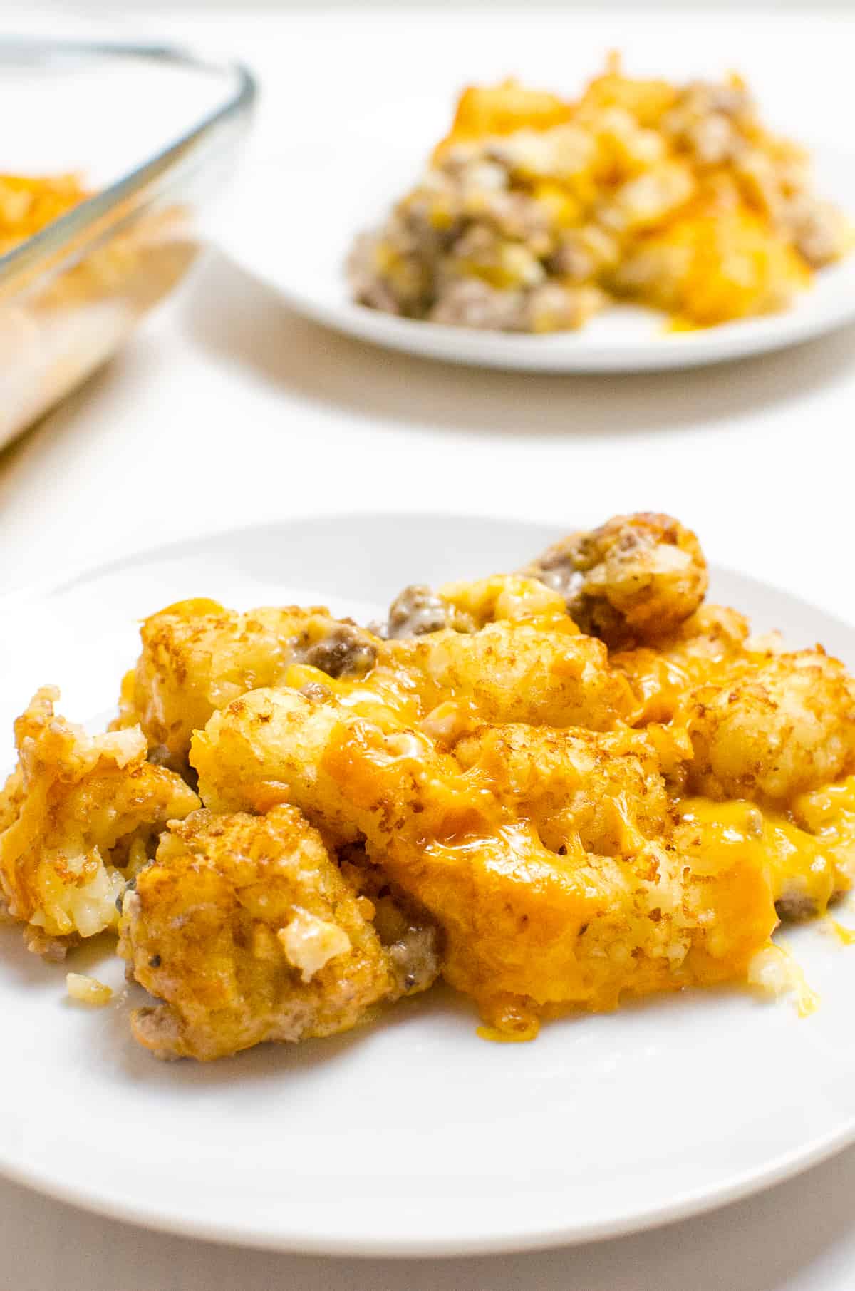 Beef Tater Tot Casserole on white place with another plate and serving in background