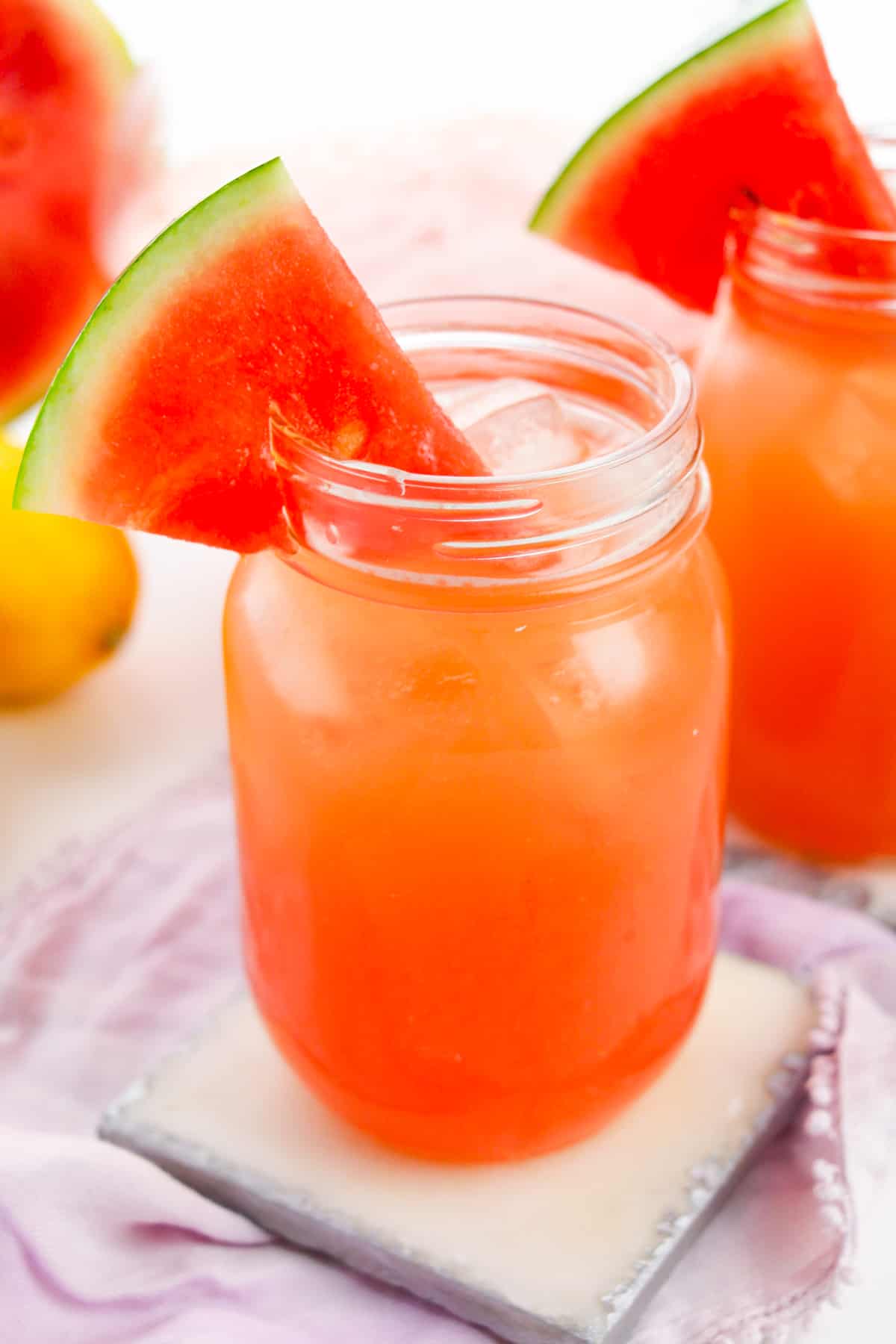 Glass mason jar filled with fresh watermelon lemonade and garnished with watermelon slice