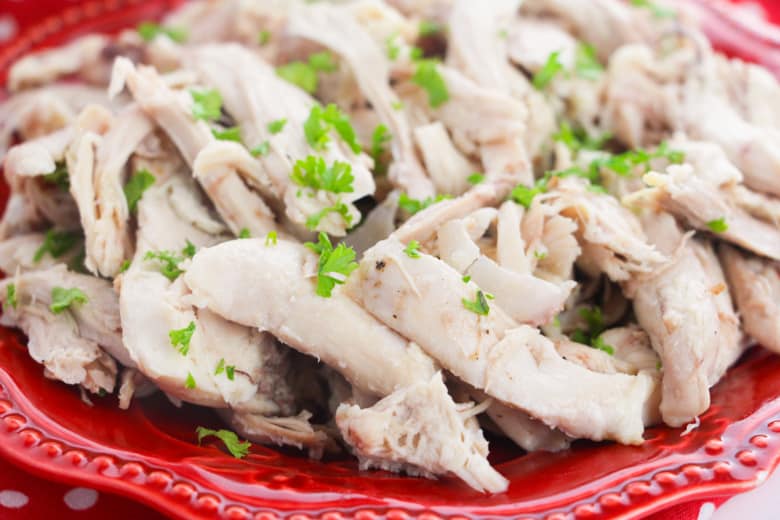 thick pieces of pulled chicken leg on red plate