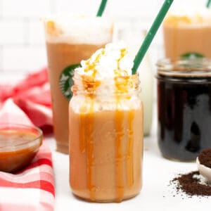 Caramel Frappuccino topped with whipped cream and caramel drizzle served in a mason jar with green straw