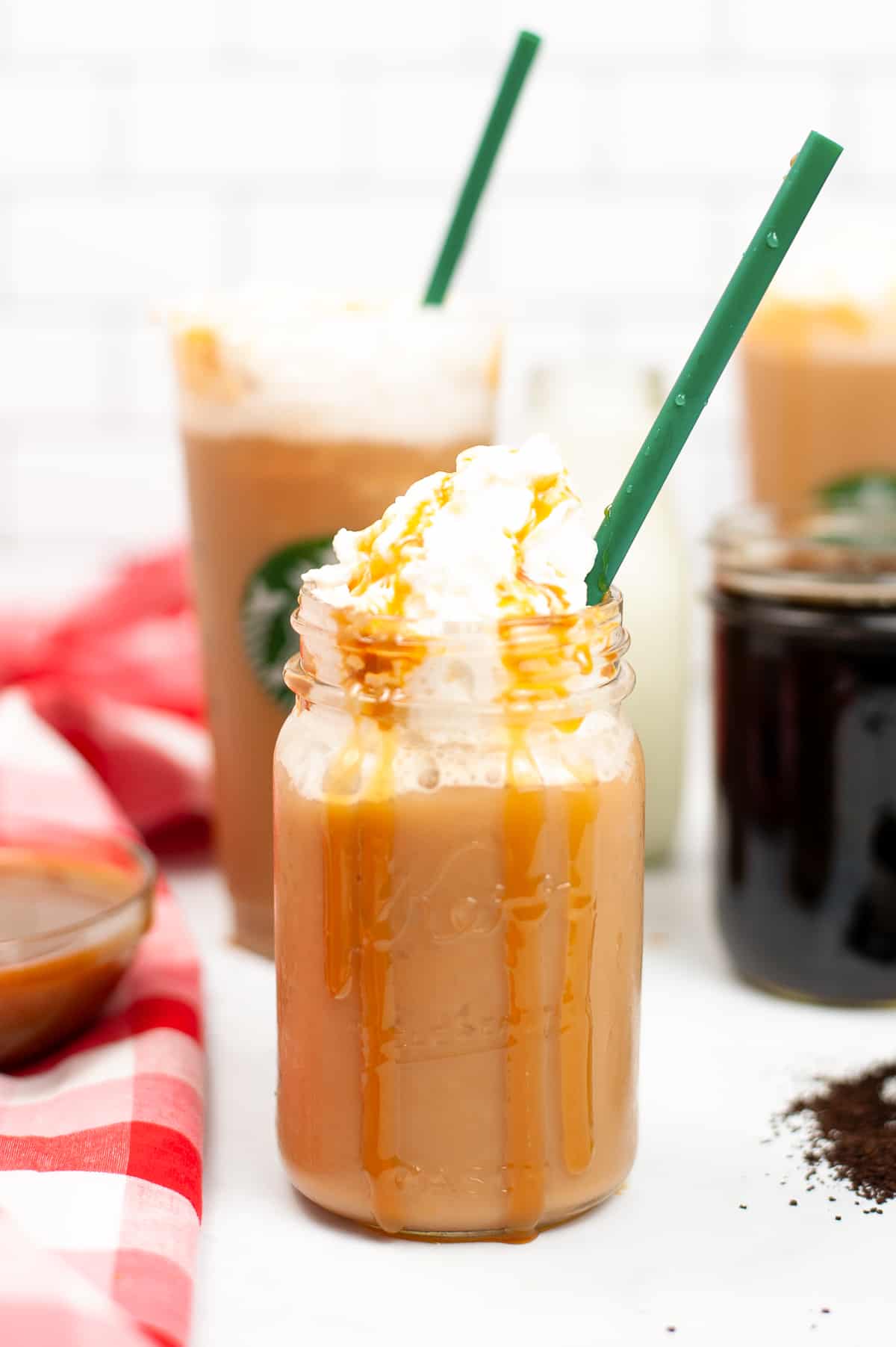 Caramel Frappuccino topped with whipped cream and caramel drizzle served in a mason jar with green straw