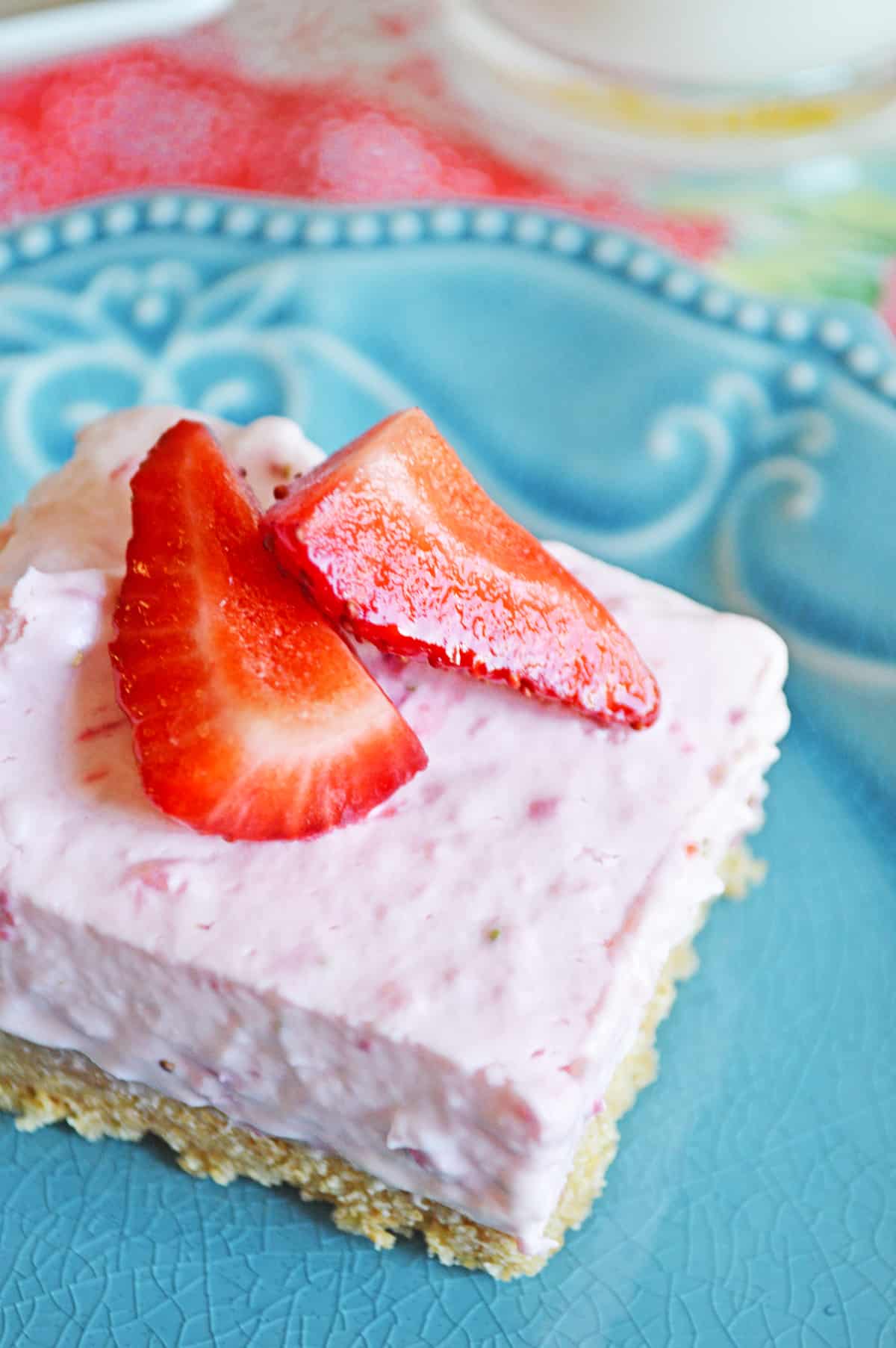 Strawberry no bake cheesecake square with graham cracker crust and topped with fresh strawberries