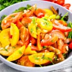 Heirloom Tomato Salad with crumbled feta on bed of lettuce in serving bowl