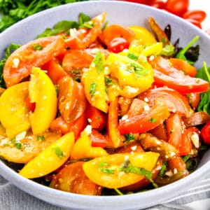 Heirloom Tomato Salad with crumbled feta on bed of lettuce in serving bowl