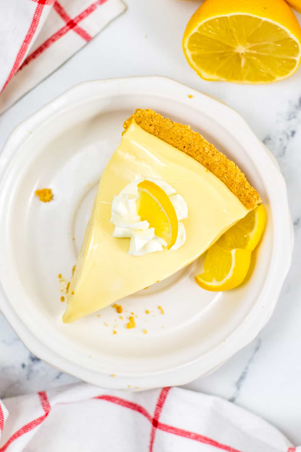 Slice of no-bake lemon pie with graham cracker crust and dollop of whipped cream
