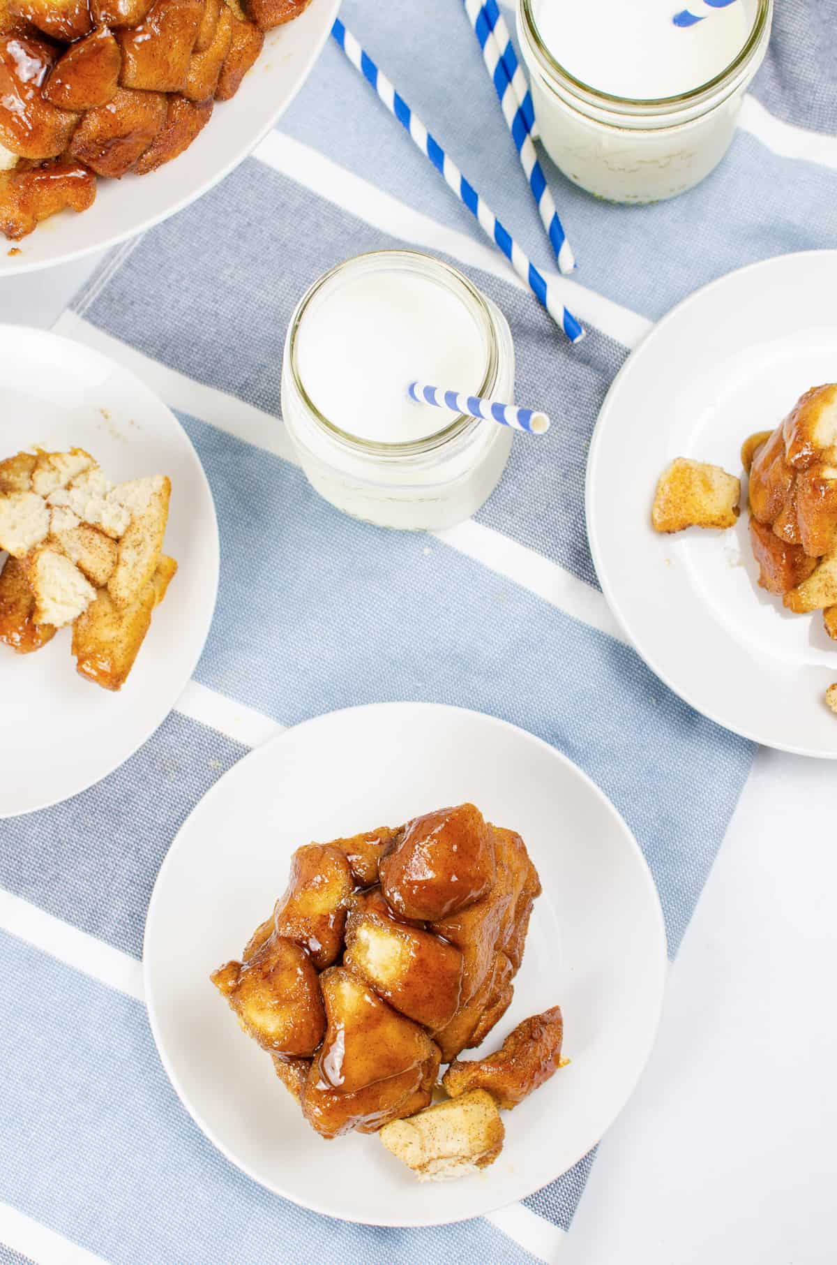 Monkey bread made with canned biscuit dough sliced into large pieces and served on white plates with glasses of milk.