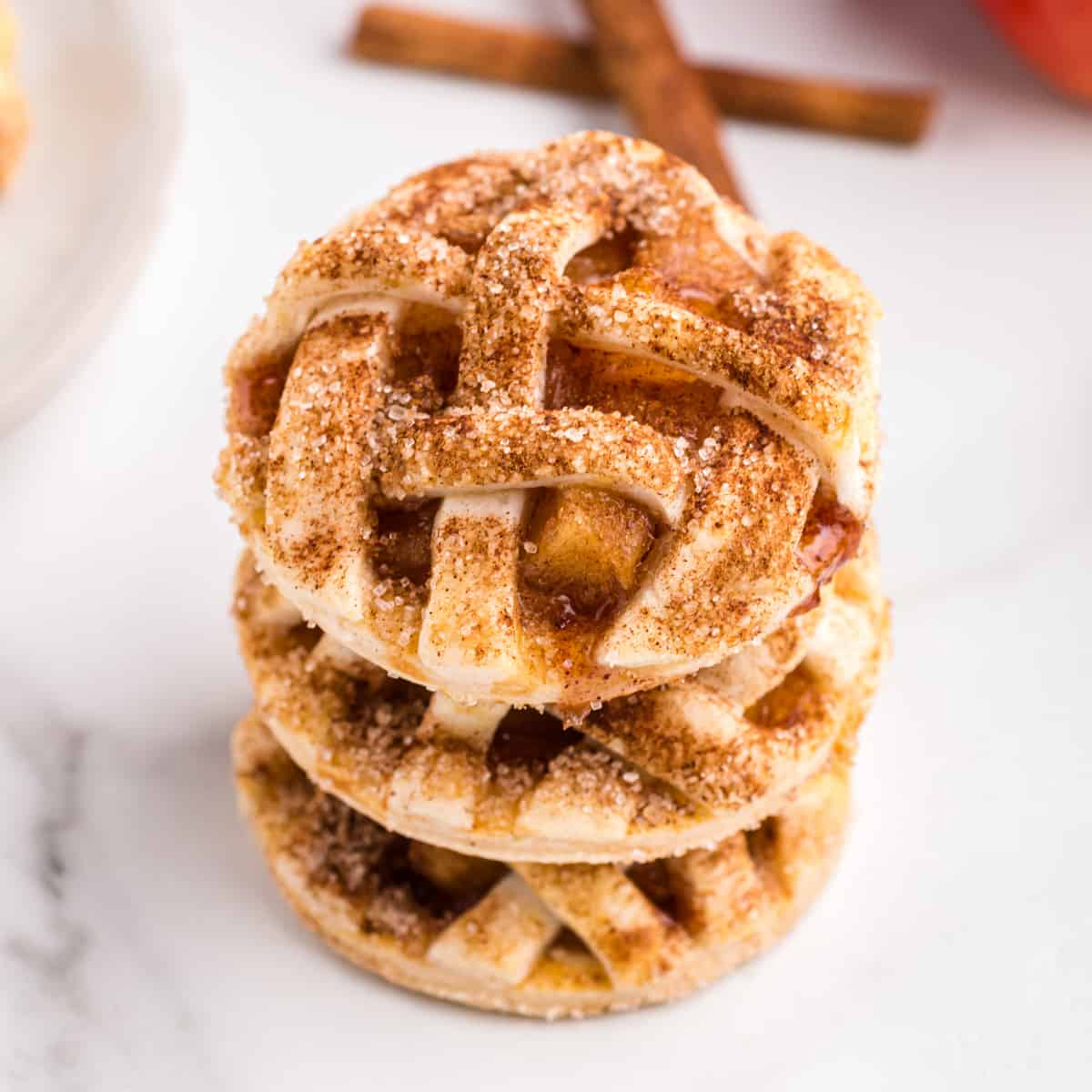 Three apple pie cookies stacked on top of one another on marble countertop