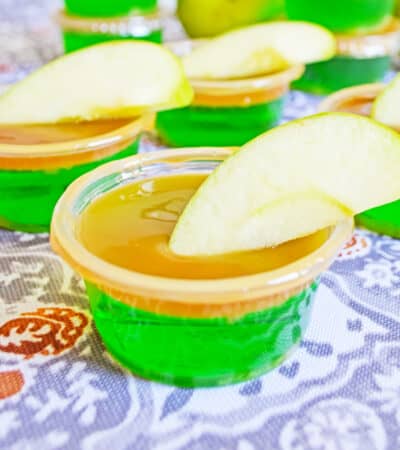 Green apple jello shot with caramel vodka, caramel topping, and fresh apple wedge.