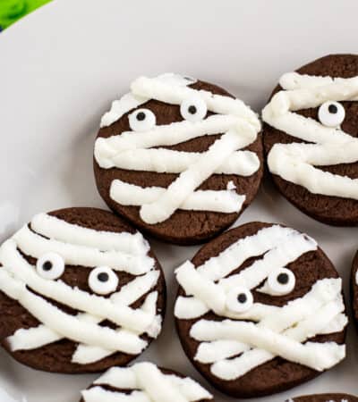 chocolate mummy cookies with strips of whit frosting and candy eyes
