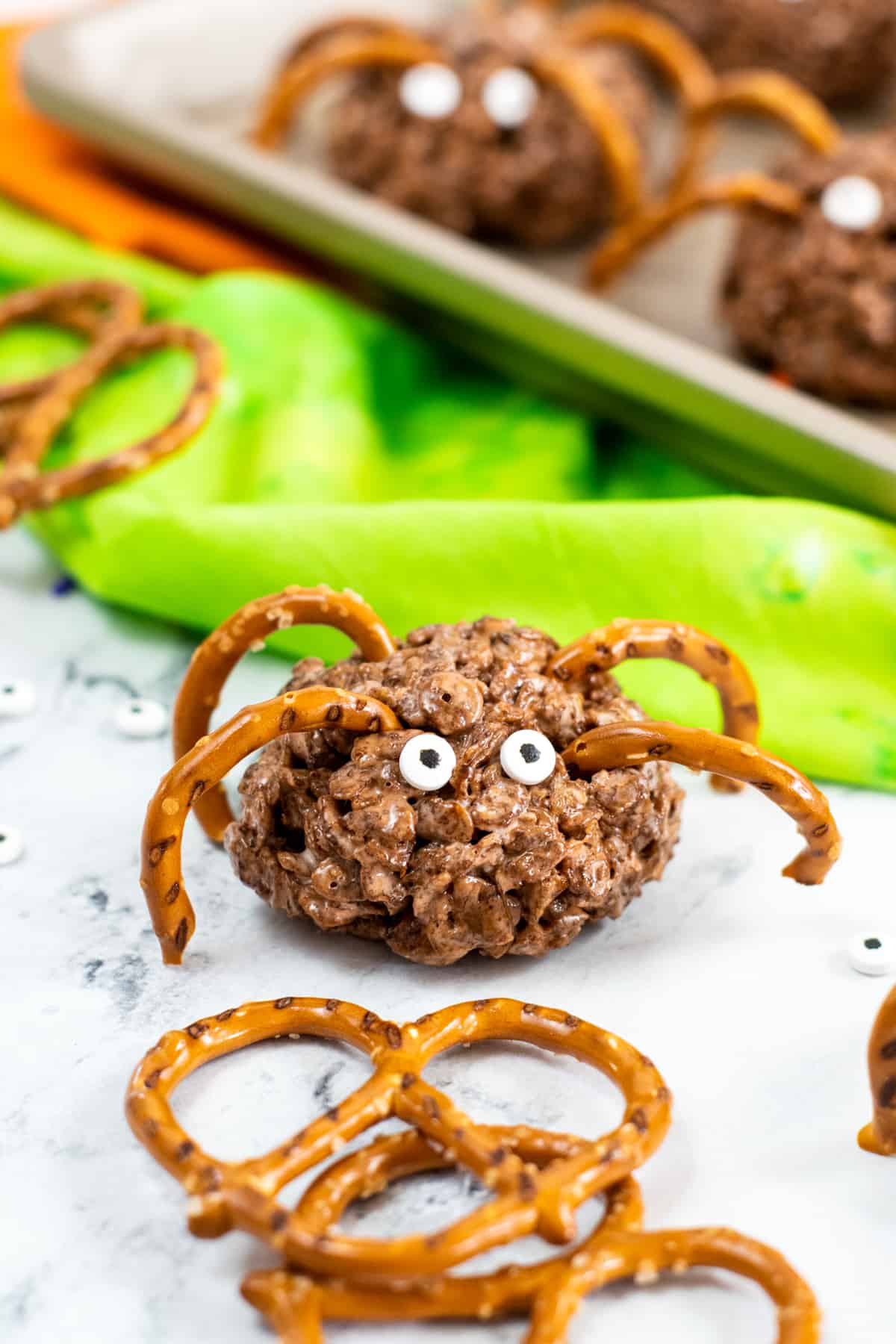 Brown rice krispies treat spiders with pretzel pieces as legs and candy eyes