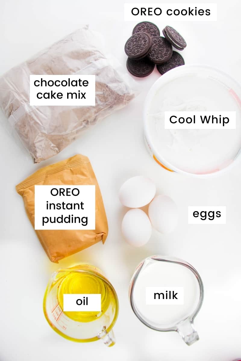 Ingredients on countertop: bag of chocolate cake mix, pile of OREO cookies, tub of Cool Whip, 3 eggs, measuring cup filled with milk, measuring cup of oil, and bag of OREO pudding mix