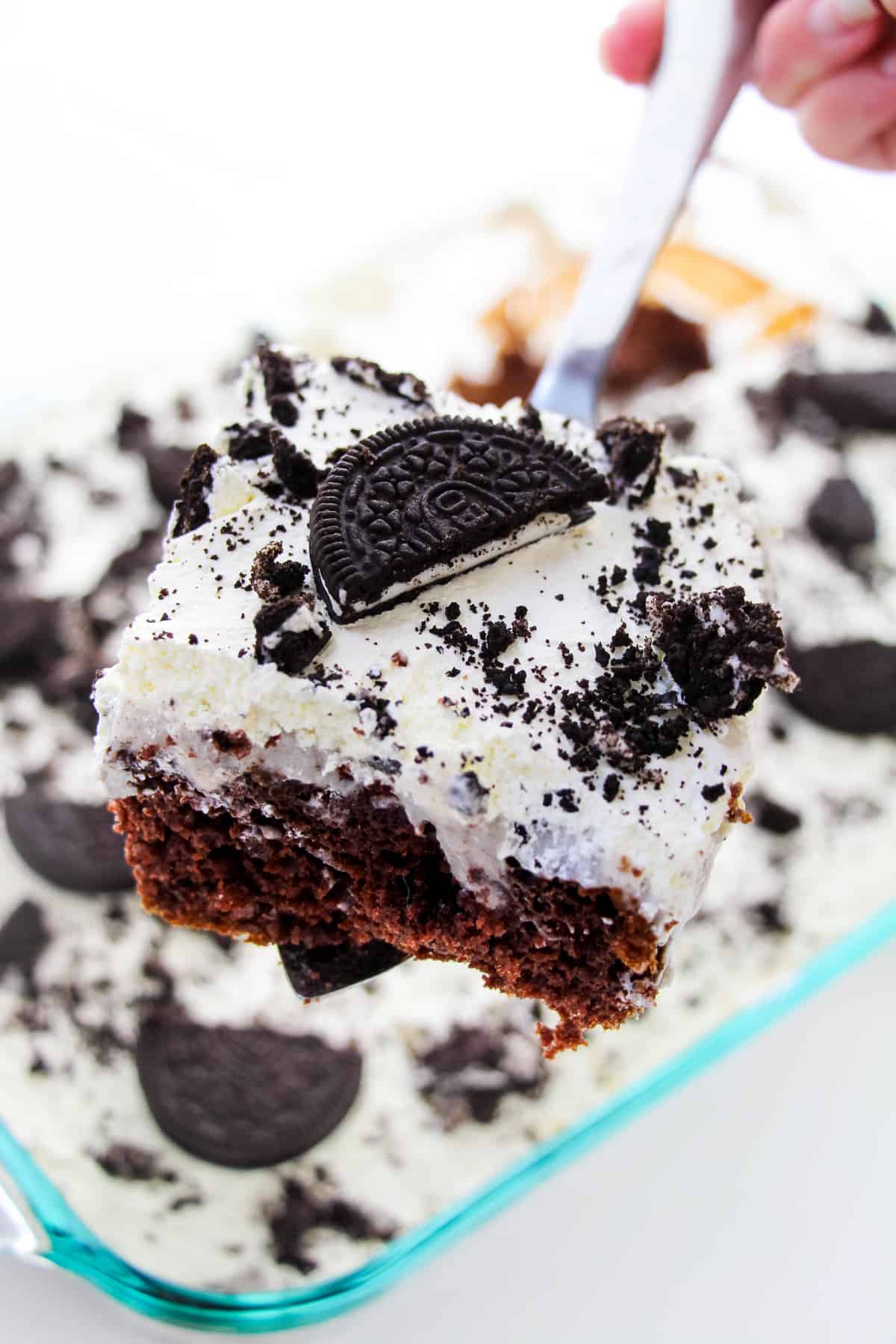Square piece of OREO pudding poke cake being removed from pan with a spatula