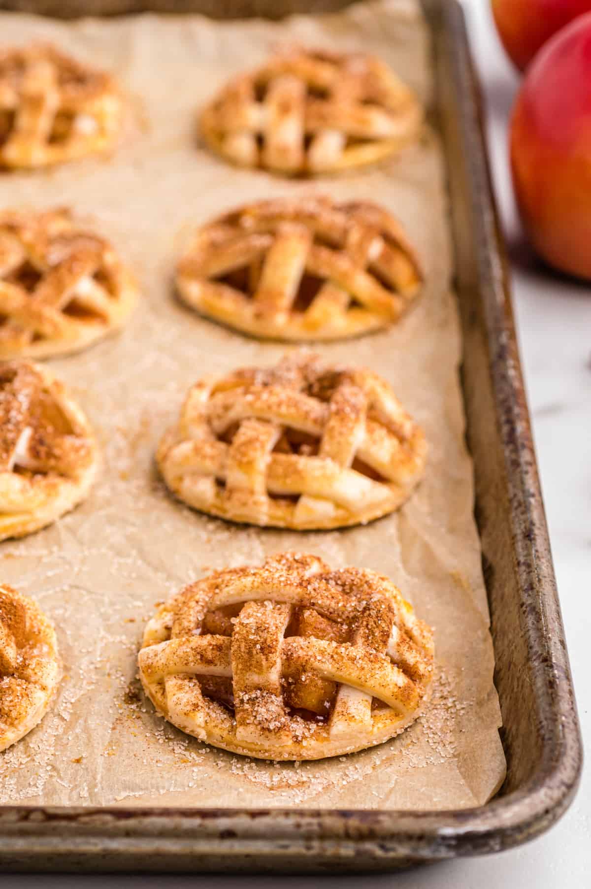 Freshly baked apple pie cookies stuffed with apple pie filling on lined baking sheet
