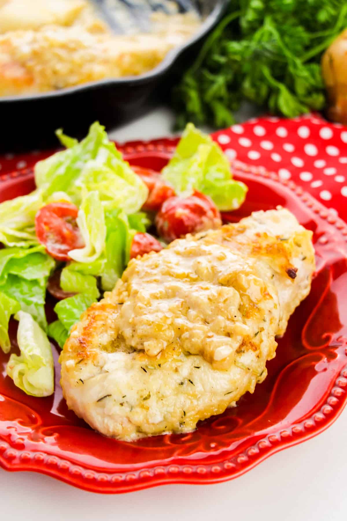 Smothered Chicken Breast served with salad on a red plate.