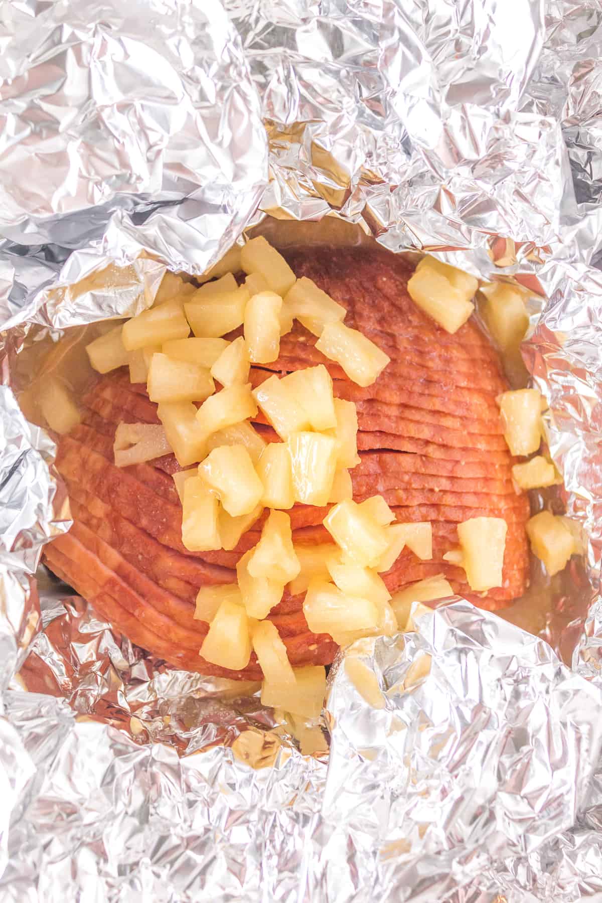 Ham with foil pulled back and pineapple glaze added